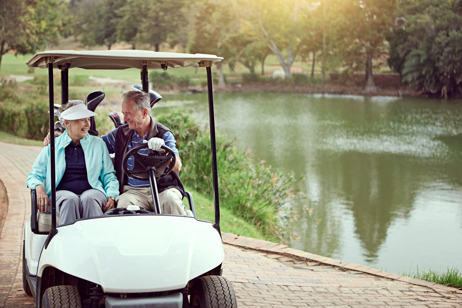 Senior couple riding together in a golf cart on a course