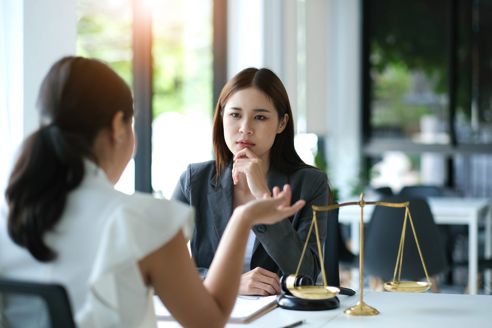 Attorney and client discussing a case at a desk with scales of justice